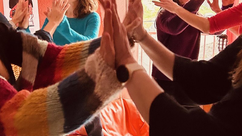 Manos de varias personas juntándose en el aire durante un momento de celebración colectiva